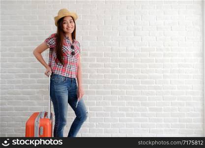 Young asian woman traveler holding smart phone and luggage in white room with copy space, people summer holiday vacation background concept