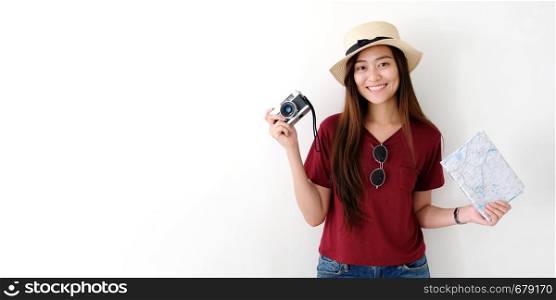 Young asian woman traveler holding vintage camera and map over white cement wall background with copy space, people summer holiday vacation background concept