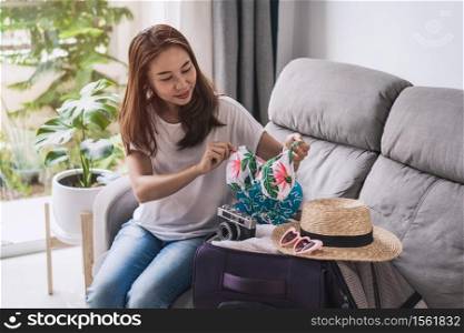 Young asian woman traveler packing her suitcase and planning for the summer vacation, Travel concept