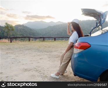 Young asian woman traveler parked car on viewpoint with enjoying the beautiful landscape during sunset.  road trip concept