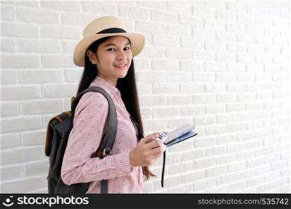 Young asian woman traveler with backpack holding vintage camera and map standing in white room with copy space, people summer holiday vacation background concept