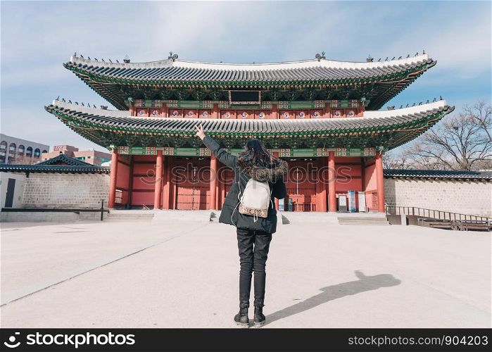 Young asian woman traveler with backpack traveling into the Deoksugung Palace's Daehanmun Gate at Seoul city, South Korea.