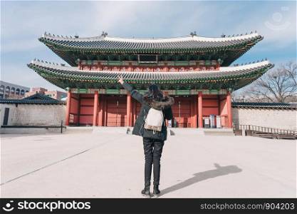Young asian woman traveler with backpack traveling into the Deoksugung Palace's Daehanmun Gate at Seoul city, South Korea.