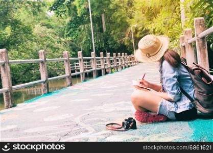 Young asian woman traveling and writing on notebook against beautiful tropical scenery