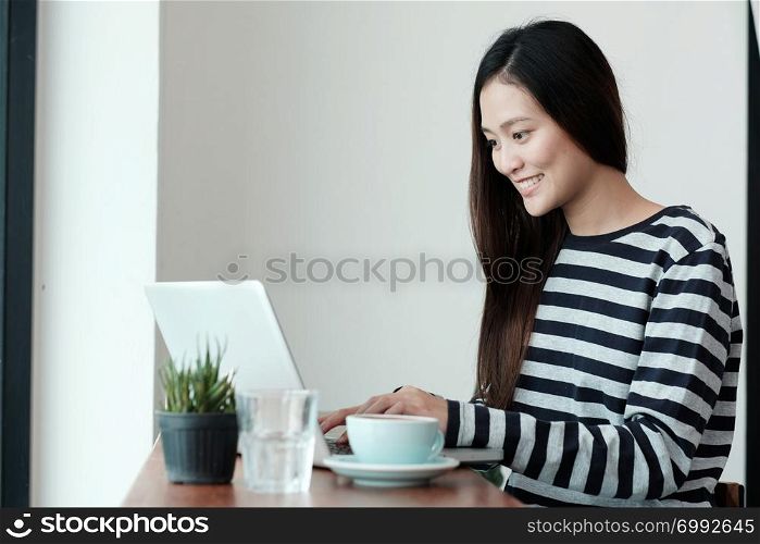 Young asian woman using laptop computer while sitting at coffee cafe background, people and technology, lifestyles