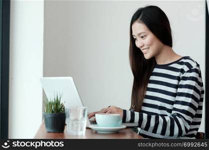 Young asian woman using laptop computer while sitting at coffee cafe background, people and technology, lifestyles