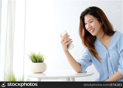 Young asian woman using smart phone with smiling, happy and relax emotion in white room background, people on phone, lifestyle