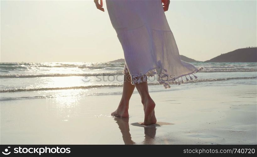Young Asian woman walking on beach. Beautiful female happy relax walking on beach near sea when sunset in evening. Lifestyle women travel on beach concept.