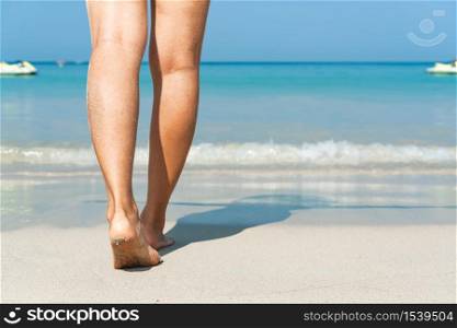 Young Asian woman walking on sand beach. Closeup detail of female feet and white sand at Phuket, Thailand. Beach travel concept.