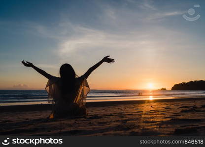 Young Asian woman watching sunset near beach, beautiful female happy relax enjoy moment when sunset in evening. Lifestyle woman travel on beach concept.