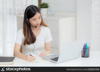 Young asian woman wearing headphone study online with e-learning on desk, girl wearing headset learning to internet with laptop computer at home, new normal, distance education and training.