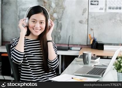 Young asian woman wearing headphones smiling with happiness while working, work at home, casual office life concept