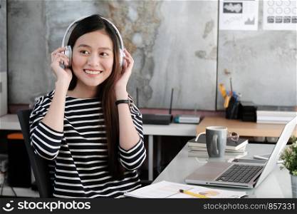 Young asian woman wearing headphones smiling with happiness while working, work at home, casual office life concept