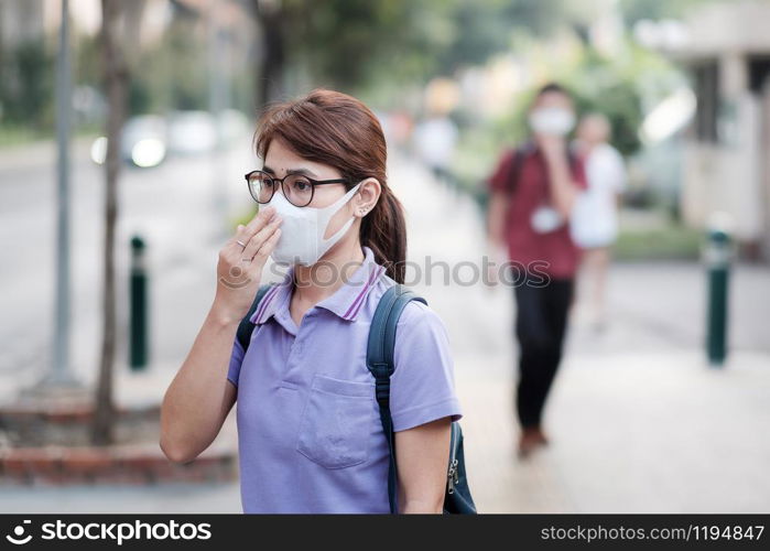 young Asian woman wearing N95 respiratory mask protect and filter pm2.5 (particulate matter) against traffic and dust city. healthcare and air pollution concept