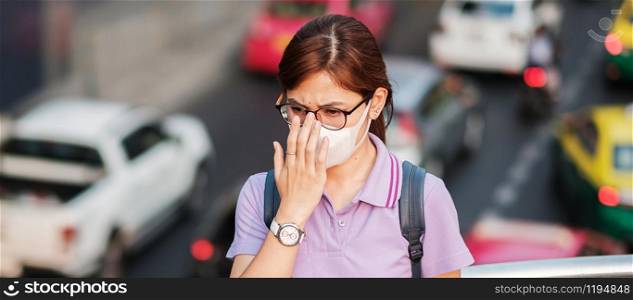 young Asian woman wearing N95 respiratory mask protect and filter pm2.5 (particulate matter) against traffic and dust city. healthcare and air pollution concept