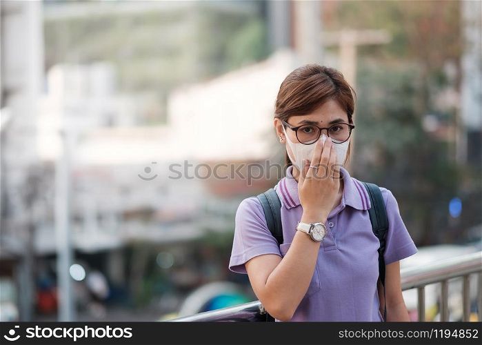 young Asian woman wearing N95 respiratory mask protect and filter pm2.5 (particulate matter) against traffic and dust city. healthcare and air pollution concept