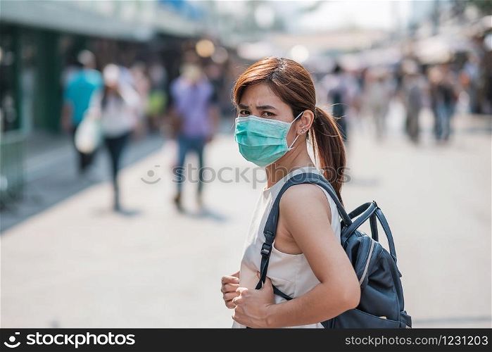 young Asian woman wearing protection mask against Novel coronavirus (2019-nCoV) or Wuhan coronavirus at Chatuchak Weekend Market, landmark and popular for tourists attractions in Bangkok, Thailand