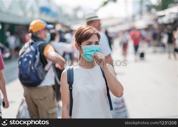 young Asian woman wearing protection mask against Novel coronavirus (2019-nCoV) or Wuhan coronavirus at Chatuchak Weekend Market, landmark and popular for tourists attractions in Bangkok, Thailand