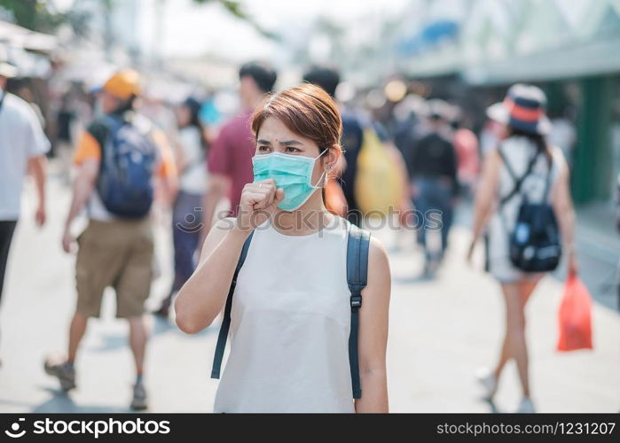 young Asian woman wearing protection mask against Novel coronavirus (2019-nCoV) or Wuhan coronavirus at Chatuchak Weekend Market, landmark and popular for tourists attractions in Bangkok, Thailand