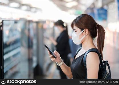 young Asian woman wearing surgical face mask against Novel coronavirus or Corona Virus Disease (Covid-19) at public train station. Hygiene, Healthcare and infection concept
