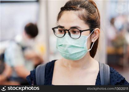 young Asian woman wearing Surgical face mask against Novel coronavirus or Corona Virus Disease (Covid-19) at public subway train. Hygiene, Healthcare and infection concept