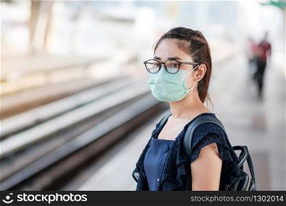 young Asian woman wearing Surgical face mask against Novel coronavirus or Corona Virus Disease (Covid-19) at public train station. Hygiene, Healthcare and infection concept