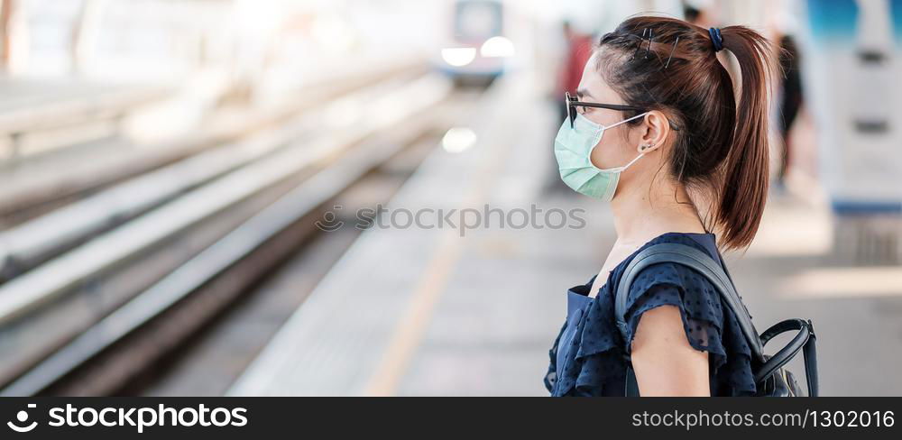 young Asian woman wearing Surgical face mask against Novel coronavirus or Corona Virus Disease (Covid-19) at public train station. Hygiene, Healthcare and infection concept