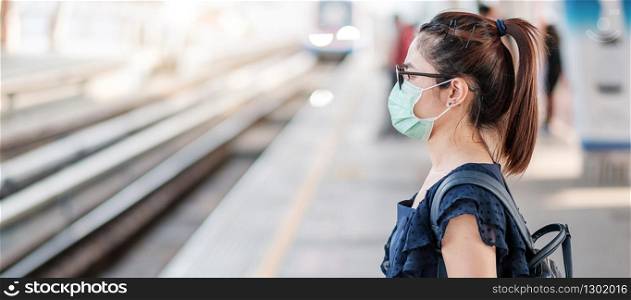 young Asian woman wearing Surgical face mask against Novel coronavirus or Corona Virus Disease (Covid-19) at public train station. Hygiene, Healthcare and infection concept