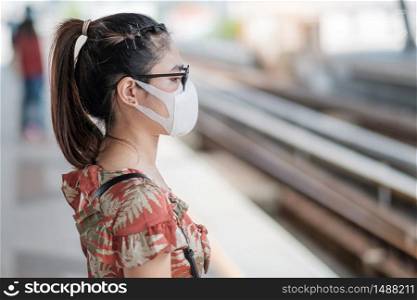 young Asian woman wearing Surgical face mask protect coronavirus inflection at public train station. social distancing, new normal and life after covid-19 pandemic