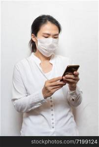 Young Asian woman wearing surgical mask prevent using smart mobile phone isolated on white background,Wuhan coronavirus (COVID-19) outbreak prevention in public area. Health care and medical concept.