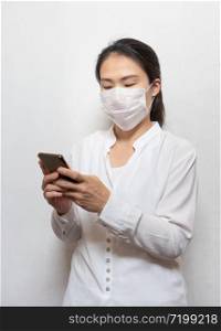 Young Asian woman wearing surgical mask prevent using smart mobile phone isolated on white background,Wuhan coronavirus (COVID-19) outbreak prevention in public area. Health care and medical concept.