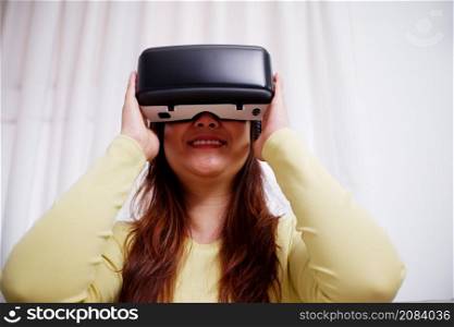 Young asian woman wearing virtual reality glasses at home. VR headset. VR concept.