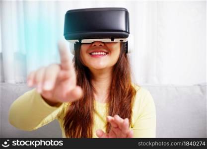 Young asian woman wearing virtual reality glasses, hand touching the air. VR headset. VR concept.