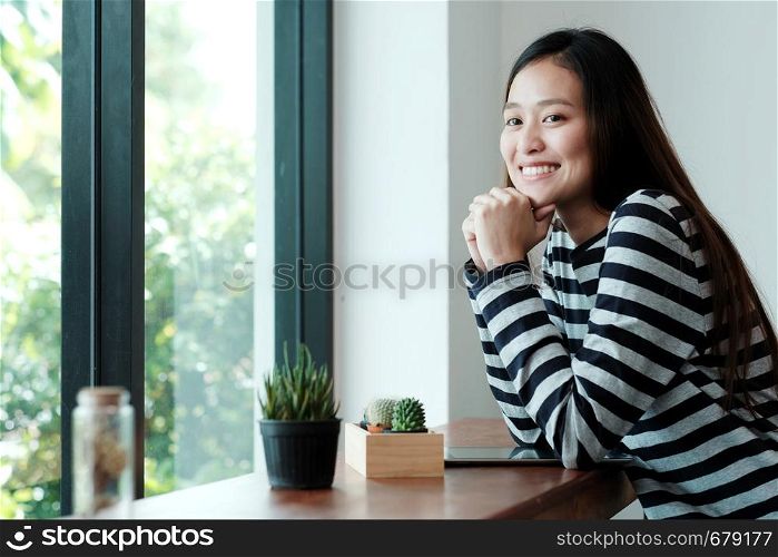 Young asian woman with digital tablet sitting in cafe background with smiling face, people and technology lifestyle
