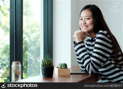 Young asian woman with digital tablet sitting in cafe background with smiling face, people and technology lifestyle