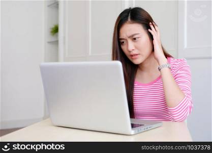 Young asian woman with frustrated expression while working with laptop computer, working from home, casual office lifestyle