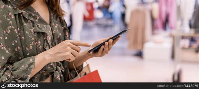 Young asian woman with shopping bags using smart phone and shopping at mall, Woman lifestyle concept, Web banner with copy space