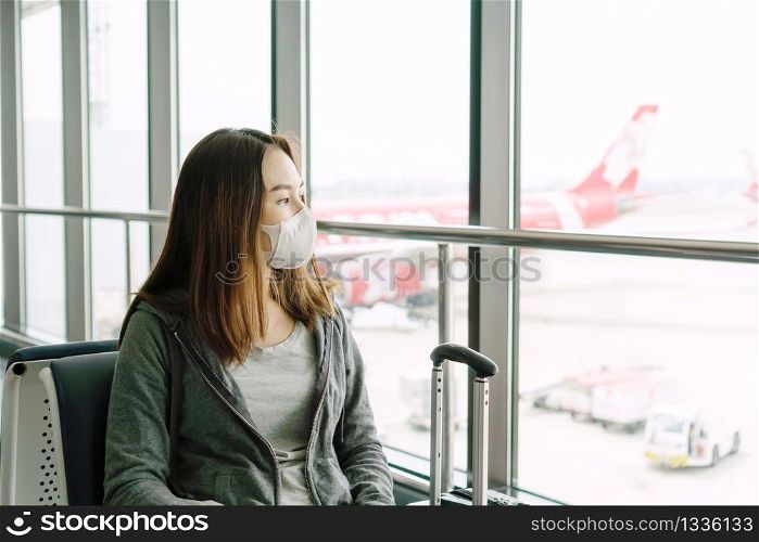 Young Asian woman with surgical mask face protection sitting at the airport terminal. Protection Coronavirus(Covid-19) and Air pollution pm2.5 concept.