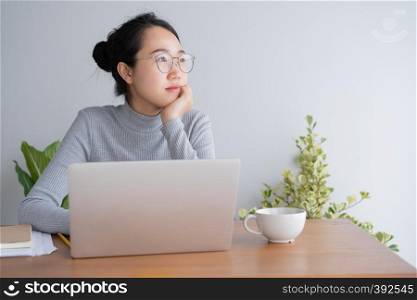 Young asian woman working on laptop in the home office desk. And sit at table resting chin on hand.