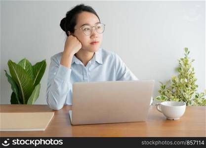 Young asian woman working on laptop in the home office desk. And sit at table resting chin on hand.