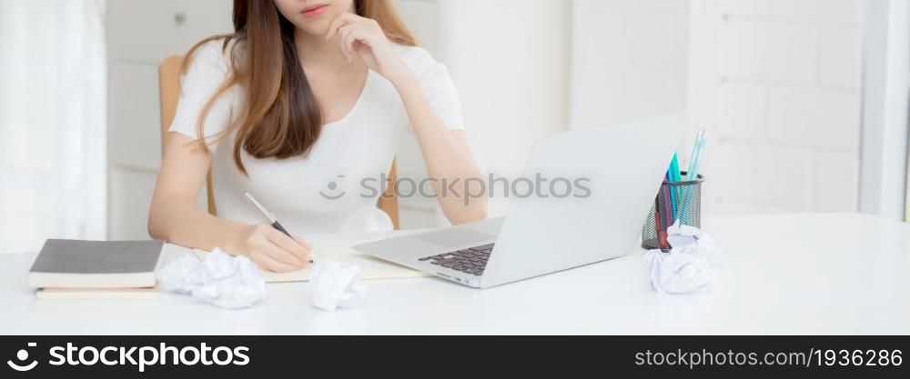 Young asian woman working with laptop computer think idea project and paper crumpled having problem on table at home, girl using notebook with frustrated and trouble, business and freelance concept.