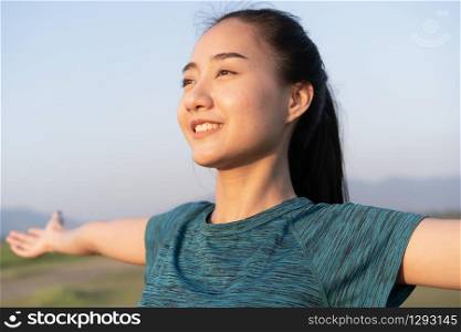 Young Asian women are exercising with yoga while standing outdoor in summer at morning, Asia girl take care of their health with meditation. Close- up of smile on face. Concept wellness and lifestyle