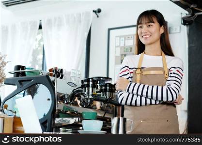 Young asian women barista standing with smiling face in font of cafe counter background, small business owner, food and drink industry concept