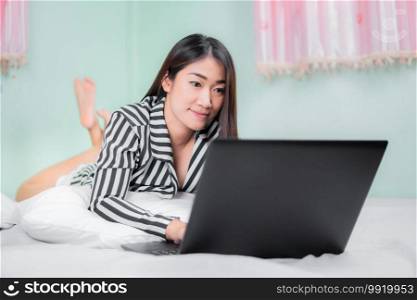 Young asian women use laptop computers at home in the bedroom. work from home concept.