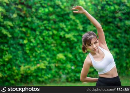 Young asian women warm up in a park before jogging.