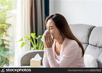 Young asian women with allergies feeling unwell using tissues and sneezing at home
