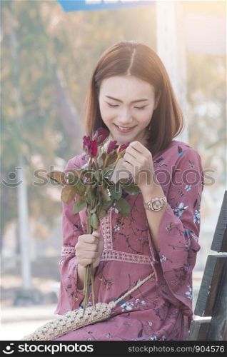 Young asian women with roses sitting on bench in park