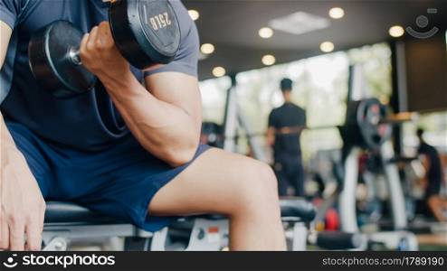 Young athlete Asian guy exercising doing lifting dumbbell fat burning workout in fitness class. Sportsman recreational activity, functional training, people working out, healthy lifestyle concept.