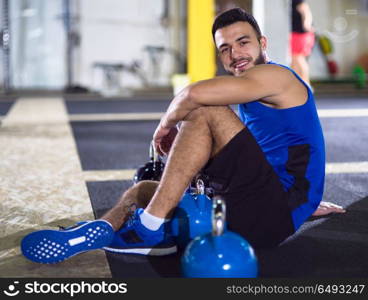 young athlete man sitting on the floor and relaxing before a hard training at crossfitness gym. young athlete man sitting on the floor and relaxing