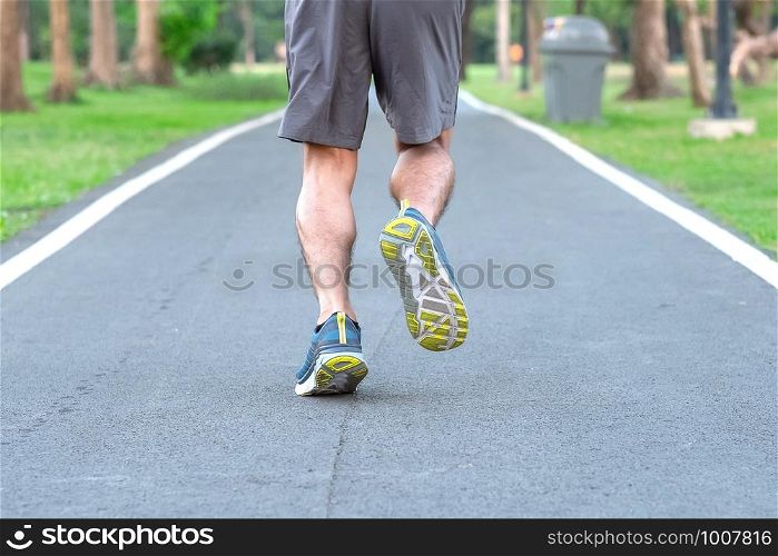 Young athlete man with running shoes in the park outdoor, male runner jogging on the road outside, asian Fitness walking and exercise on footpath in morning. wellness and sport concepts